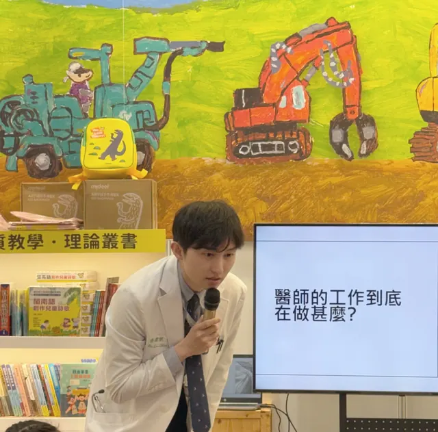 凌濼傑醫師穿白袍拿麥克風對小朋友說話